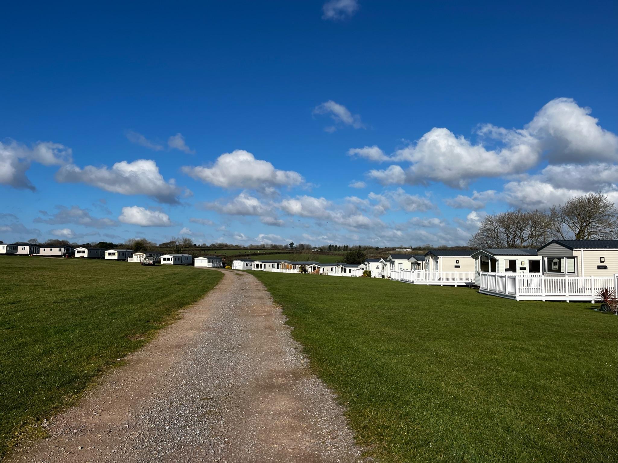 Side view of caravans surrounding a large field, which curves round to the left